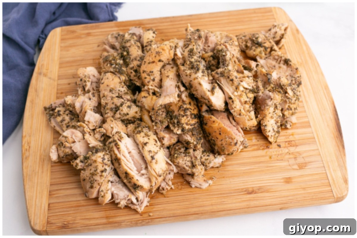 Set-It-and-Forget-It Chicken Gyros 8 Cooked chicken cut into thick strips on a wooden cutting board, ready for gyro assembly.
