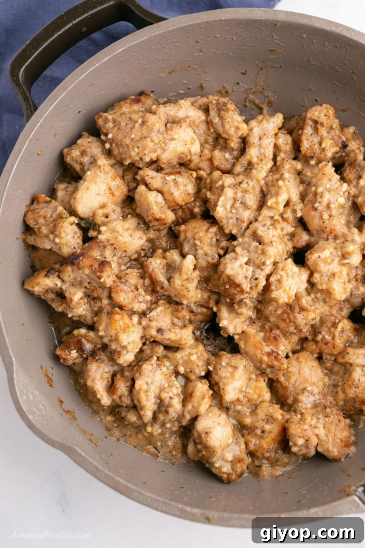 A brown skillet with boneless chicken thigh pieces in a rich garlic butter sauce, ready to be served.
