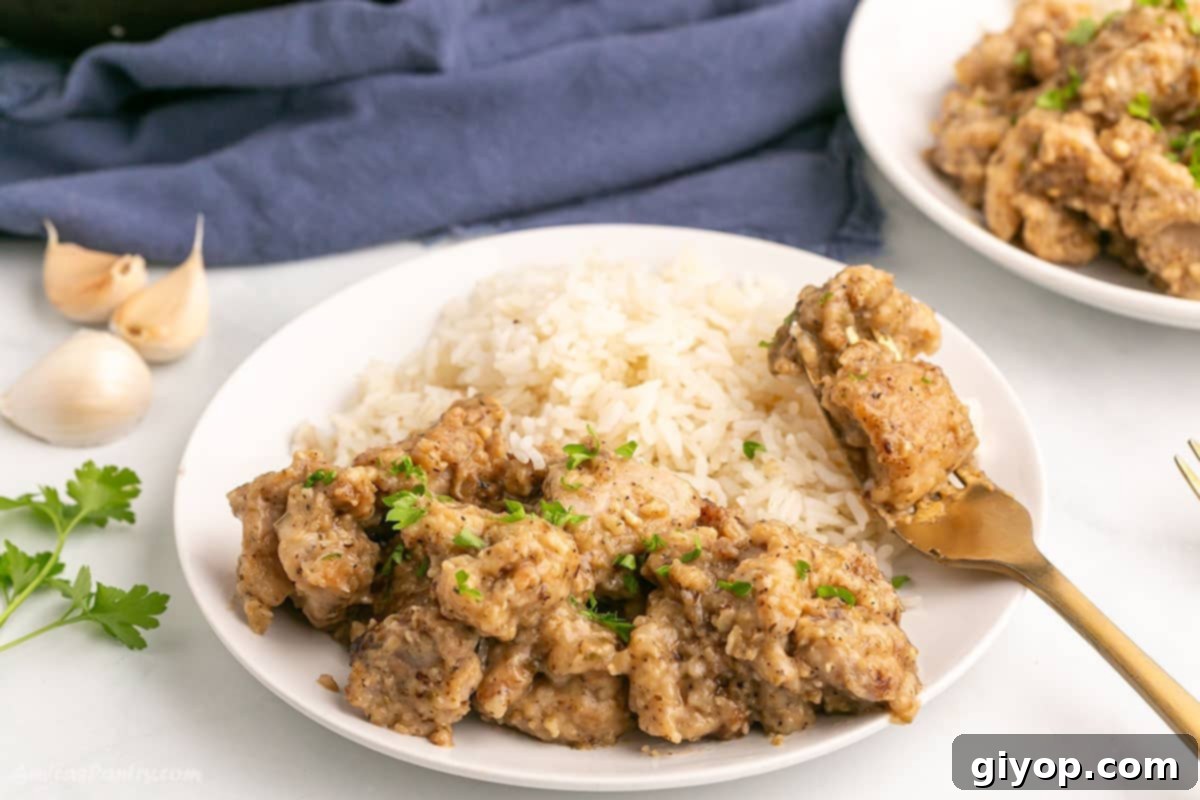 Close-up of golden-brown chicken thigh pieces swimming in a rich, glossy garlic butter sauce within a skillet.
