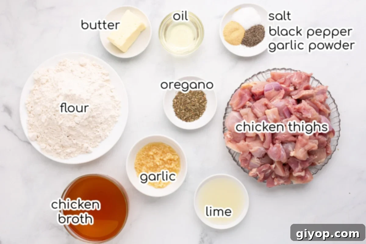 Ingredients for garlic chicken laid out on a clean white kitchen counter, including chicken thighs, butter, garlic, lime, and herbs.