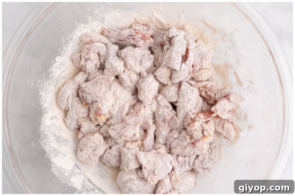 Chicken thigh pieces thoroughly dredged in flour, ready for searing.