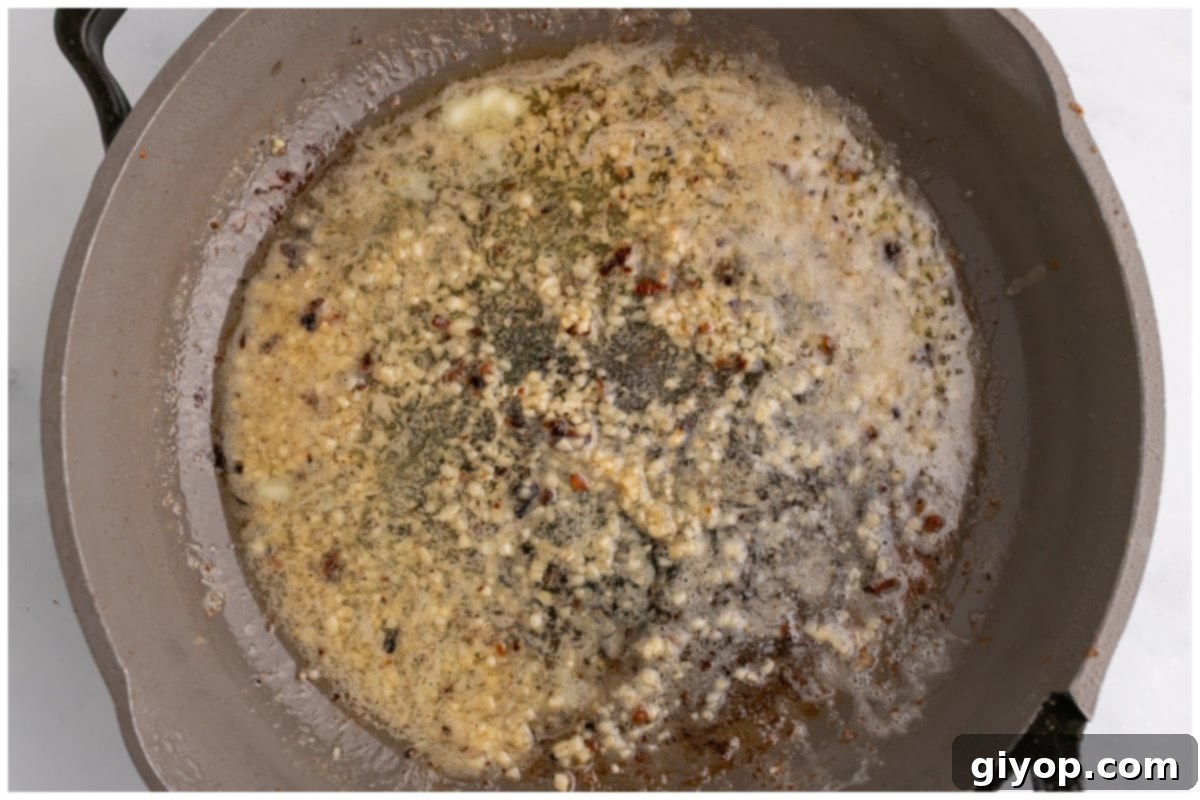 Finely chopped garlic cloves sautéing in melted butter in a skillet, filling the air with aroma.