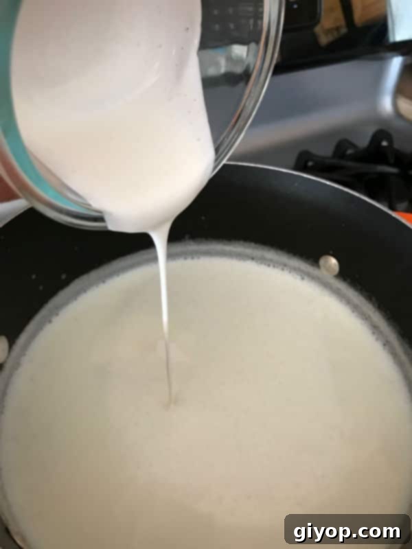 A close up of a bowl of milk on a stove, with Rice pudding