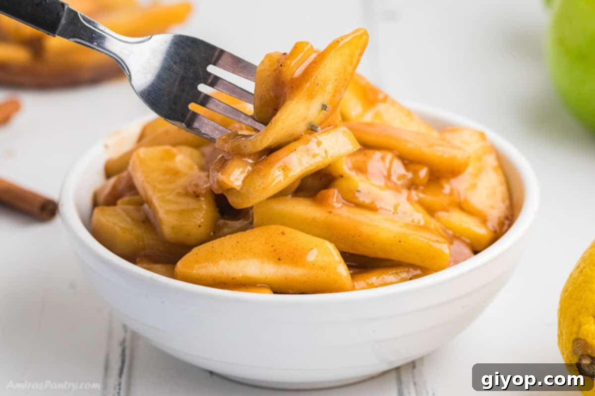 A fork lifting a piece of perfectly fried apple, showcasing its tender texture and glossy coating.