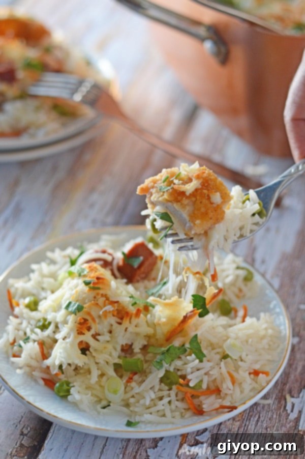 A serving of Cheesy Chicken and Rice Casserole on a white plate, with a fork, showcasing chicken, rice, and vegetables.