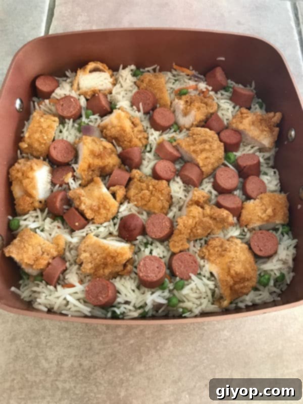 Cooked chicken strips and sliced hot dogs added to the fluffy rice and vegetables in the pot.