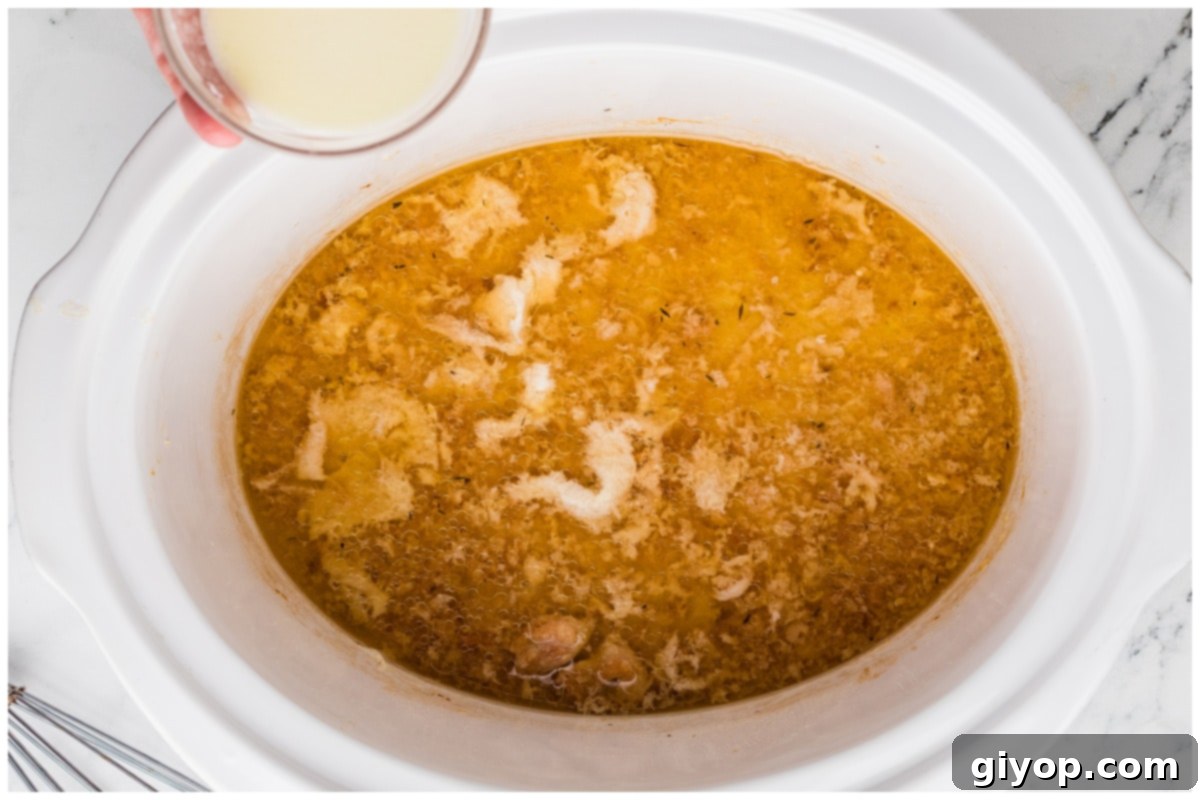 A smooth cornstarch and lemon juice slurry being poured into the slow cooker to thicken the piccata sauce.