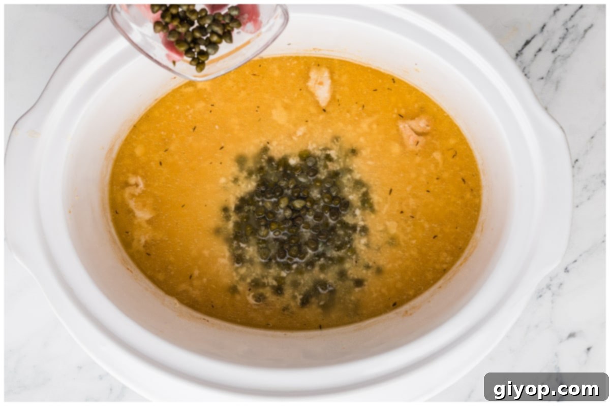 Adding capers, lightly rinsed and drained, to the simmering piccata sauce in the slow cooker for their distinctive briny flavor.