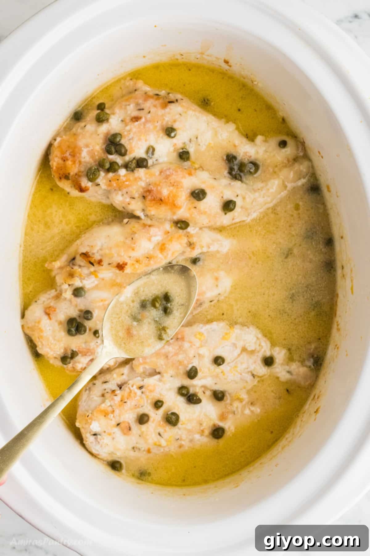 A spoon scooping some rich, golden piccata sauce, highlighting its texture and color.