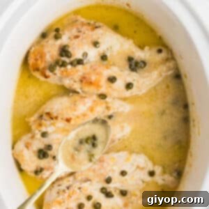 A spoon with piccata sauce over a white slow cooker, showcasing the delicious meal.