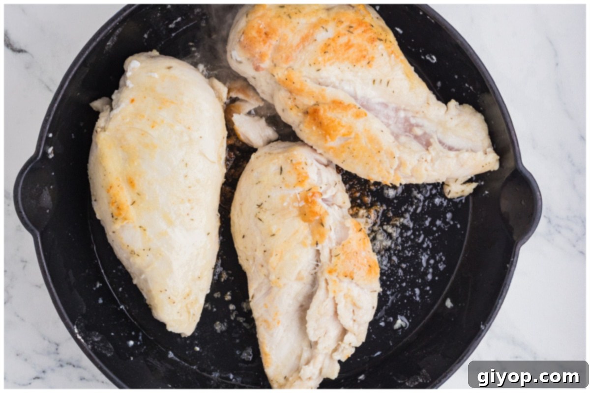 Chicken breasts searing to a perfect golden brown in a large skillet, developing rich flavors.