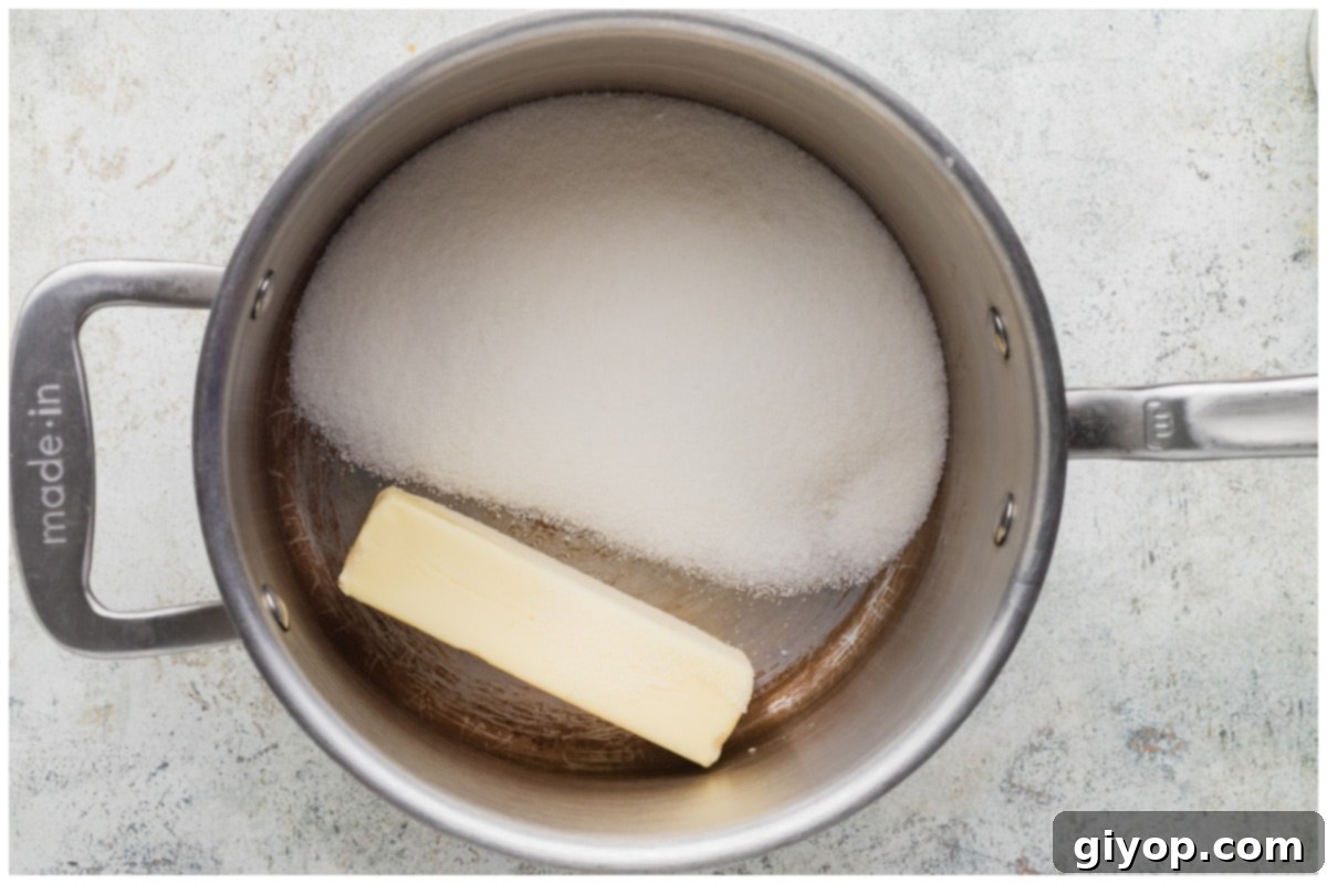 A stainless steel pot with butter and sugar, ready to be heated.
