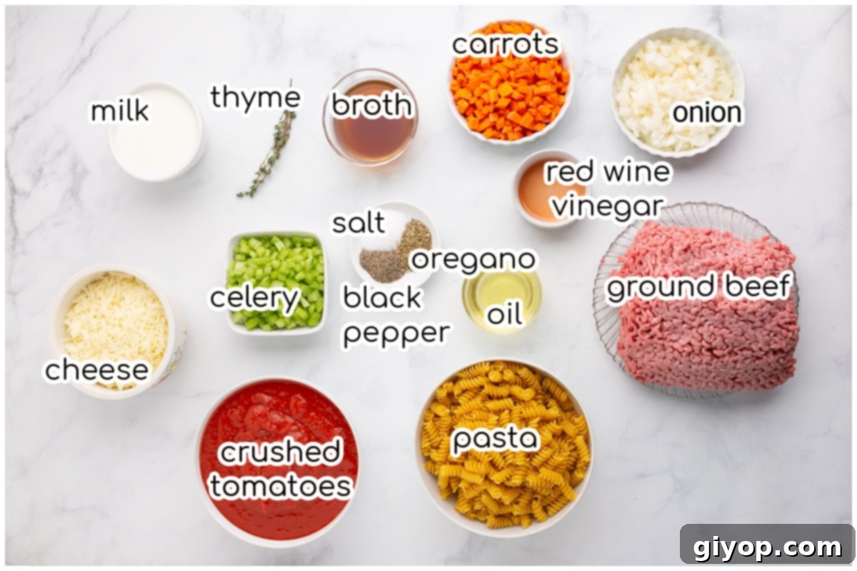 A selection of fresh ingredients laid out on a kitchen countertop, including finely diced carrots, celery, onion, olive oil, ground beef, crushed tomatoes, beef broth, oregano, thyme, salt, pepper, and whole milk, ready for preparing the baked Bolognese pasta.