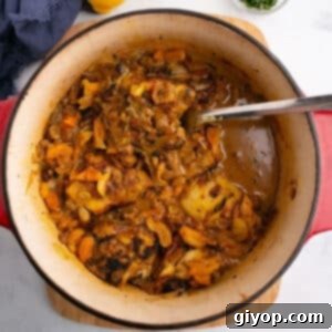 An overhead image for chicken tagine with apricots with a spoon in the pot, highlighting the rich colors and textures of the dish.