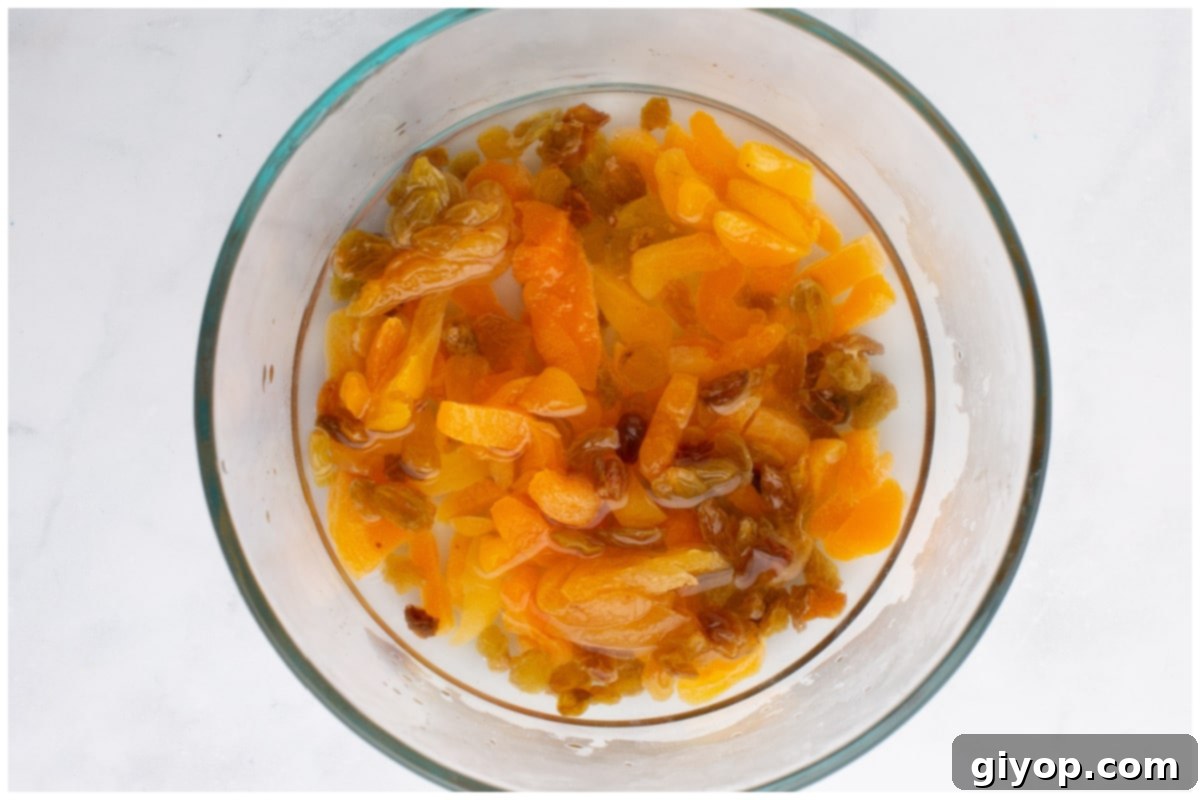 Dry apricots and golden raisins soaking in a bowl of hot water, plumping up before being added to the tagine.
