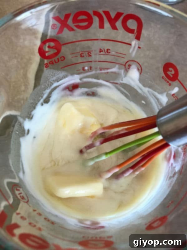 A cup containing the Tangzhong mixture after butter and milk have been added, ready for eggs.