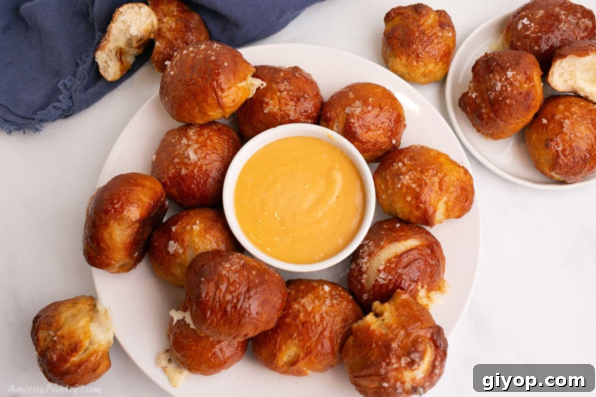 Cheese Pretzel balls on a white platter with a bowl of cheese dip in the center, ready for serving.