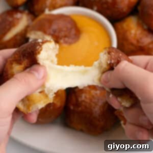 Tearing one pretzel ball to show melting cheese, highlighting the delicious filling.