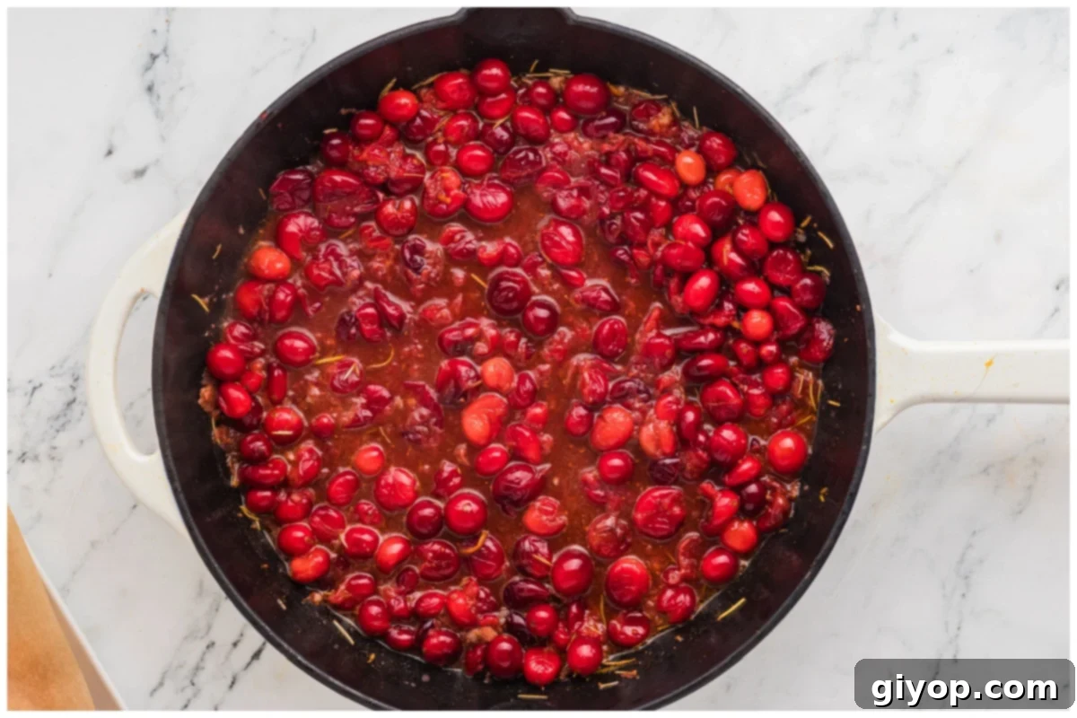 Zesty Cranberry Orange Chicken 9 Cooked cranberries in a skillet with sauce.