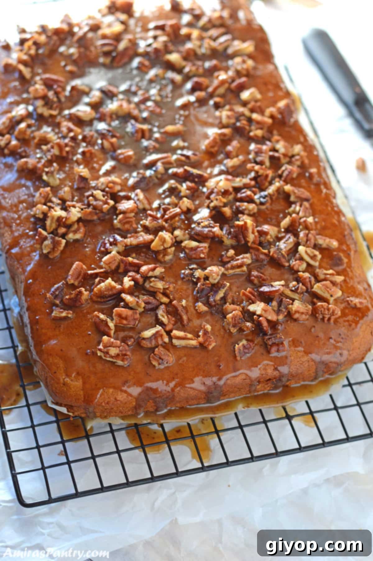 A freshly baked pumpkin sheet cake on a wire rack, with the rich browned butter-pecan glaze drizzling down the sides, ready to be served.
