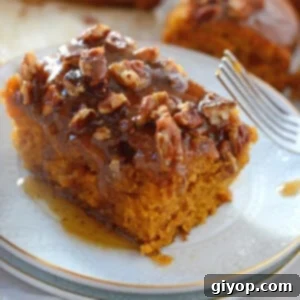 A piece of pecan pumpkin cake on a white dessert plate with a fork next to it.