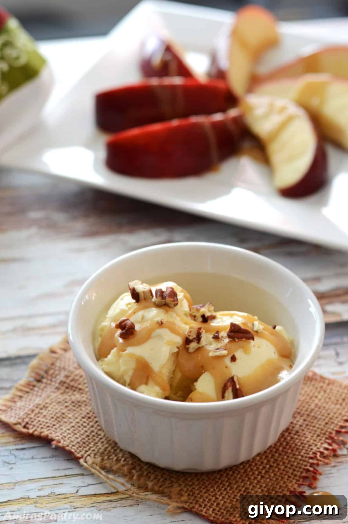 Velvet Date Caramel 7 A small white ramekin with ice cream drizzled with date caramel and pecan pieces.