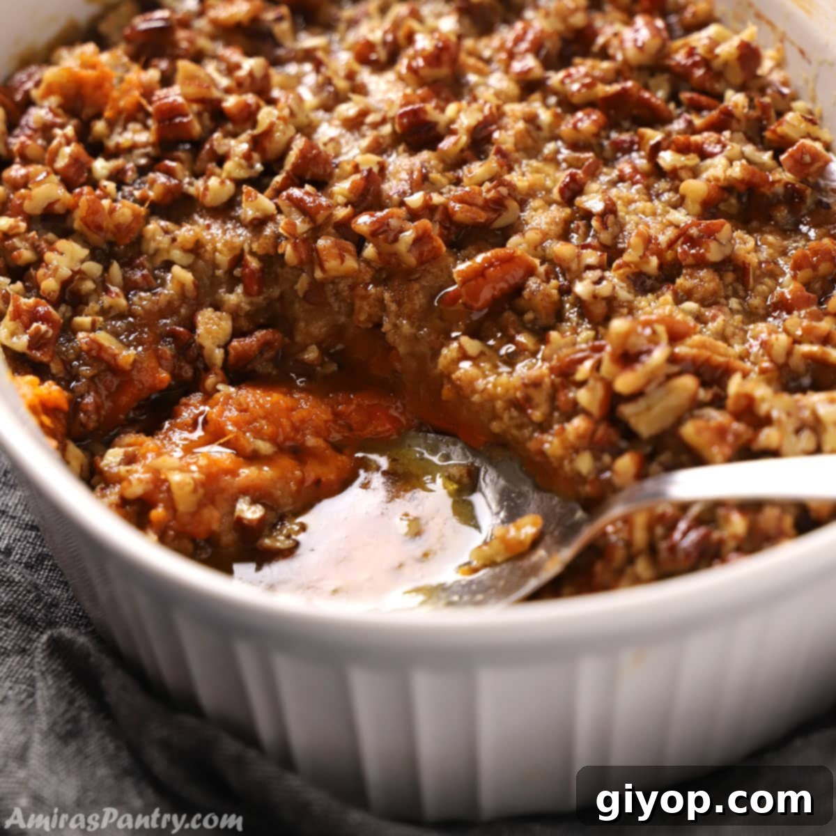 Close up of a spoon serving some golden-brown sweet potato crunch casserole, showcasing its creamy interior and crispy topping.