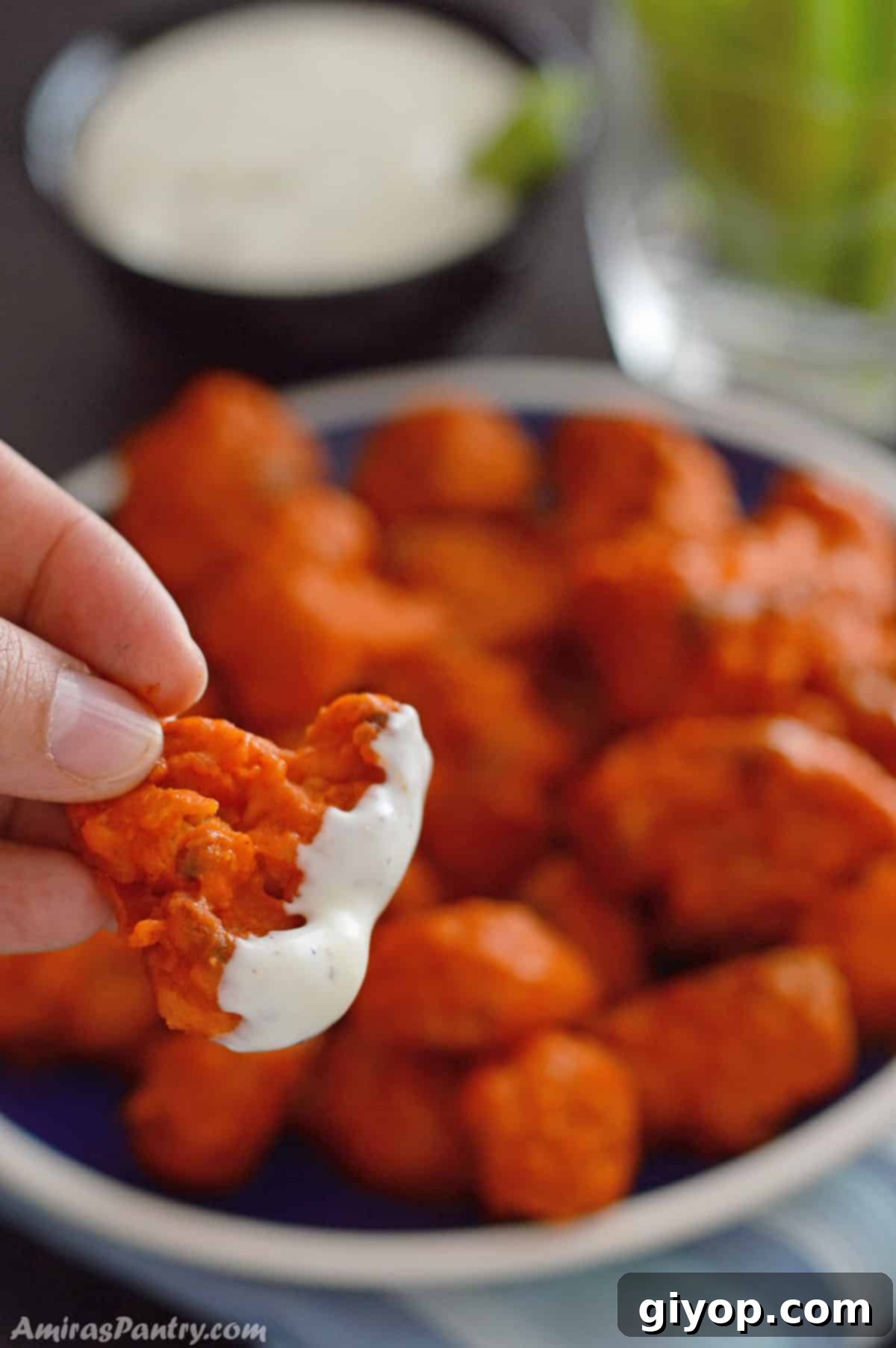 Buffalo Cauliflower Poppers 7 A hand holding a piece of crispy buffalo cauliflower dipped in ranch sauce.
