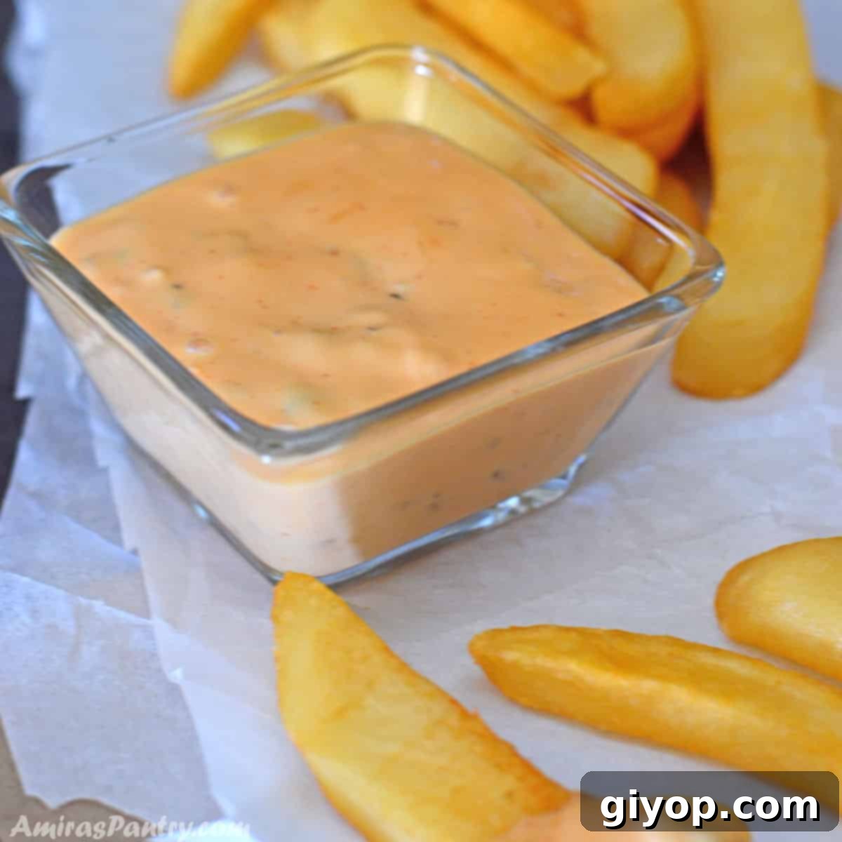 A small condiment bowl with big mac sauce with some fries.