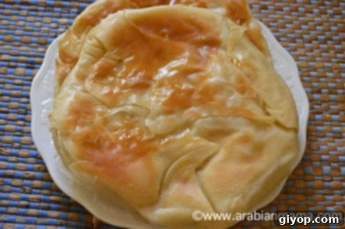 A close up of freshly baked Feteer Meshaltet topped with butter on a white plate
