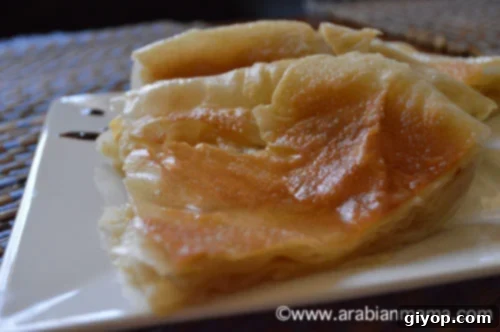 A close up of Feteer Meshaltet topped with butter on a white plate