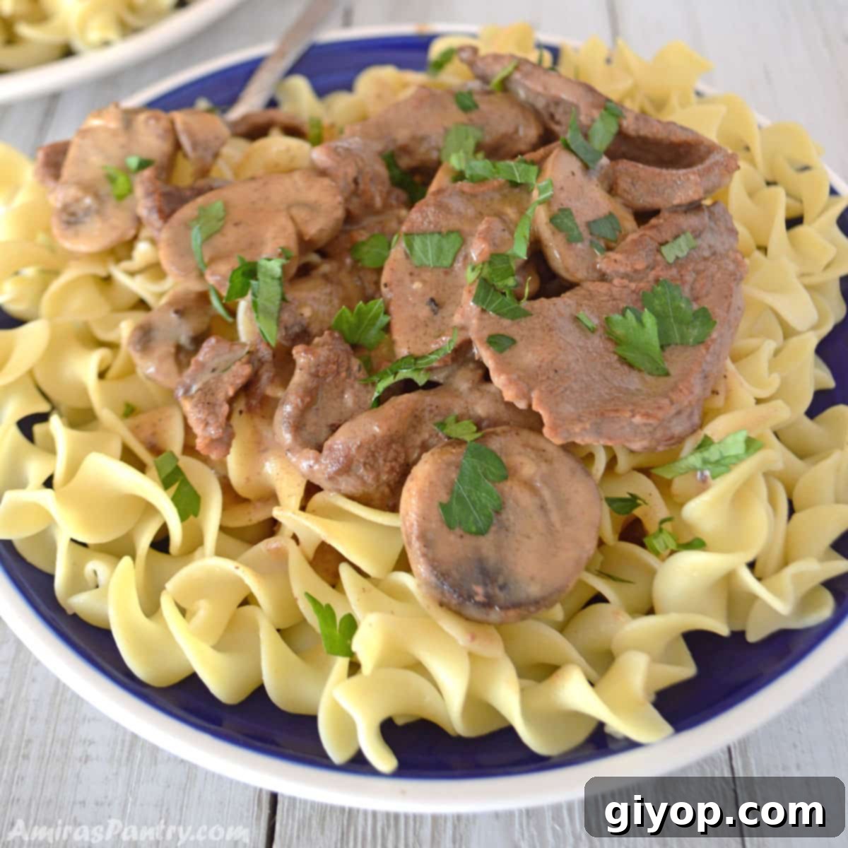 A delicious plate of homemade beef stroganoff served over egg noodles, ready to be enjoyed.