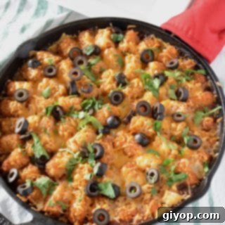 A pan with Tater tots, cheese and olives