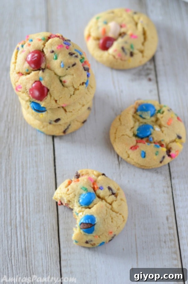 Pudding Burst Cookies 6 A stack of fireworks pudding cookies, with some scattered on the table and one with a bite taken out, highlighting its chewy interior.