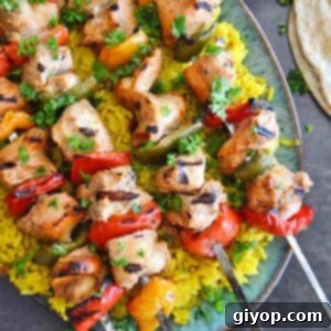 Authentic Middle Eastern Chicken Kabobs 2 A top view of a platter with chicken kabob skewers on yellow rice.