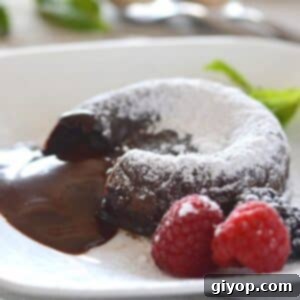 Chocolate lava cake on a white plate dusted with powdered sugar.