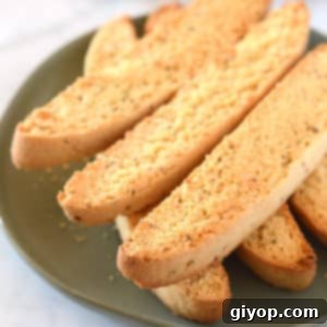 A close up of freshly baked Anise Biscotti on a plate, showcasing their golden-brown color and crunchy texture.