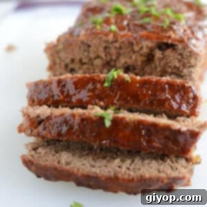 A sliced meatloaf on a white plate, ready to be served.