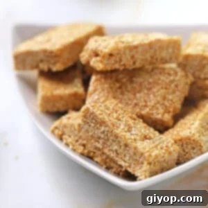 A stack of golden sesame candy bars, perfectly cut and arranged on a white plate, ready to be served.