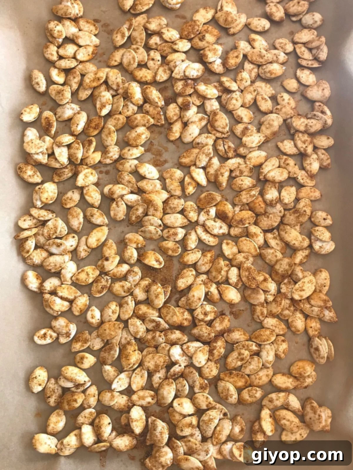 Blazing Pumpkin Seed Crunch 5 pumpkin seeds spread on a baking sheets to be baked.