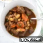 A big bowl of beef stew with a spoon in it, showcasing tender chunks of meat and vegetables.