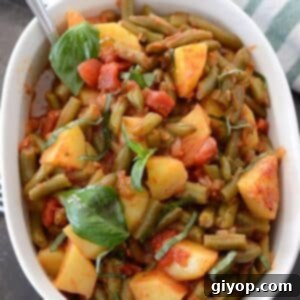 Overhead view of a white serving dish with green beans and potatoes.