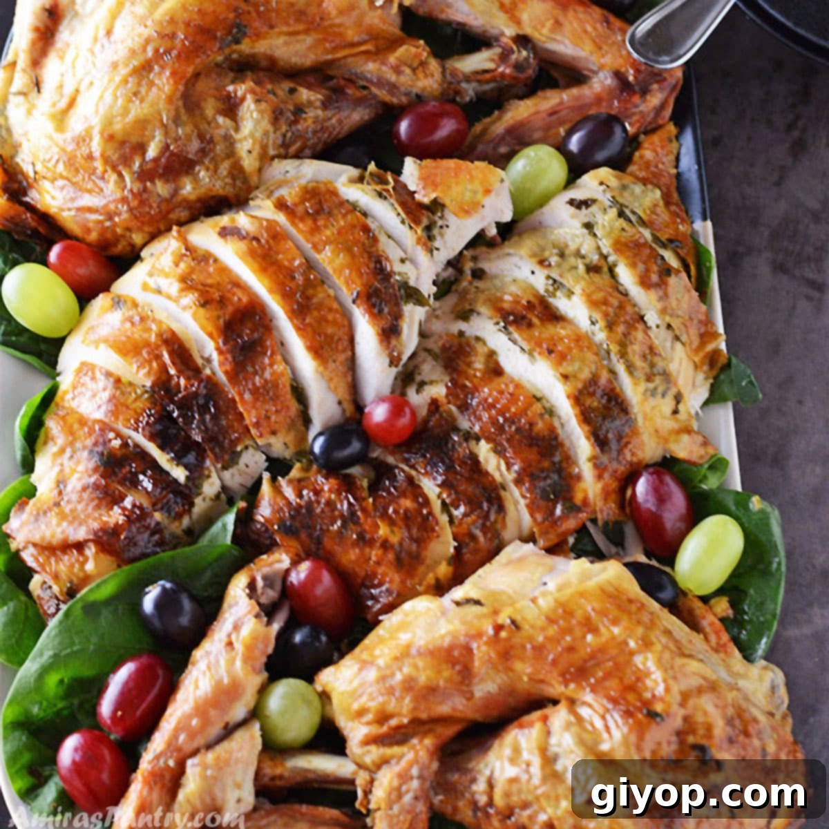 Platter of carved juicy roast turkey decorated with fruits and greens.