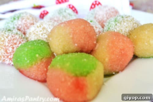A close-up of freshly made, vibrantly colored Tunisian Kaber almond balls, some rolled in sugar, ready for serving.