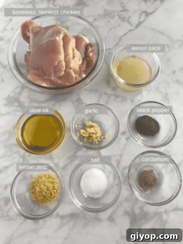 A curated selection of fresh ingredients laid out, including vibrant lemons, fragrant garlic, a bottle of golden olive oil, black peppercorns, salt, and green cardamom pods, essential for preparing the best baked lemon pepper chicken.