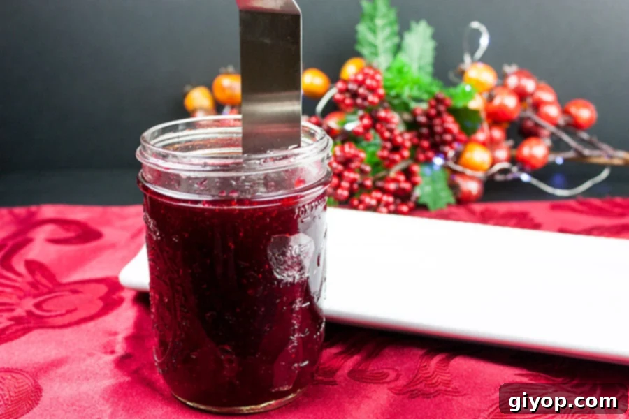 Thin spatula running around the inside of a jar to release jellied cranberry sauce.