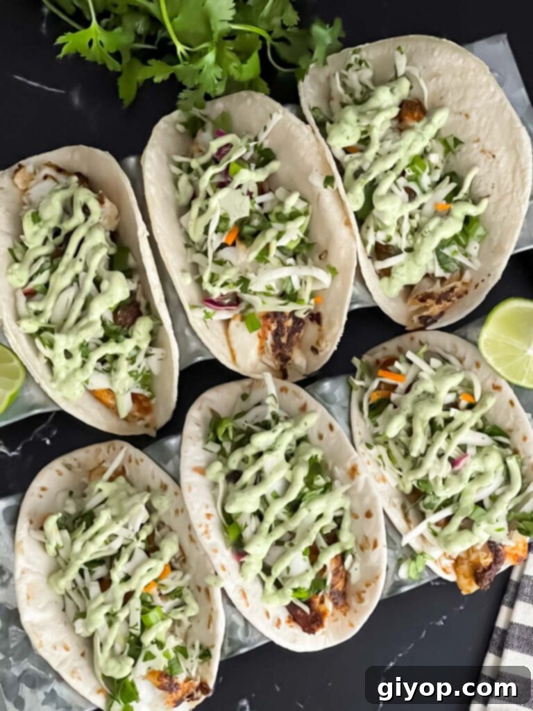 Fiery Blackened Fish Tacos 13 Two fully assembled Blackened Fish Tacos on a dark background, showcasing all the delicious layers.