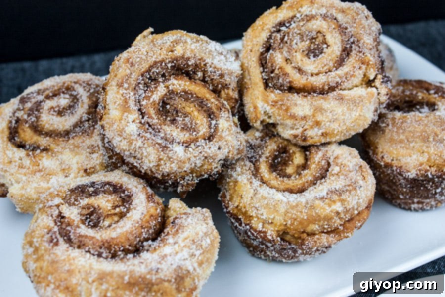 Puff pastry morning buns on a white plate, showcasing their layers and sugary glaze.