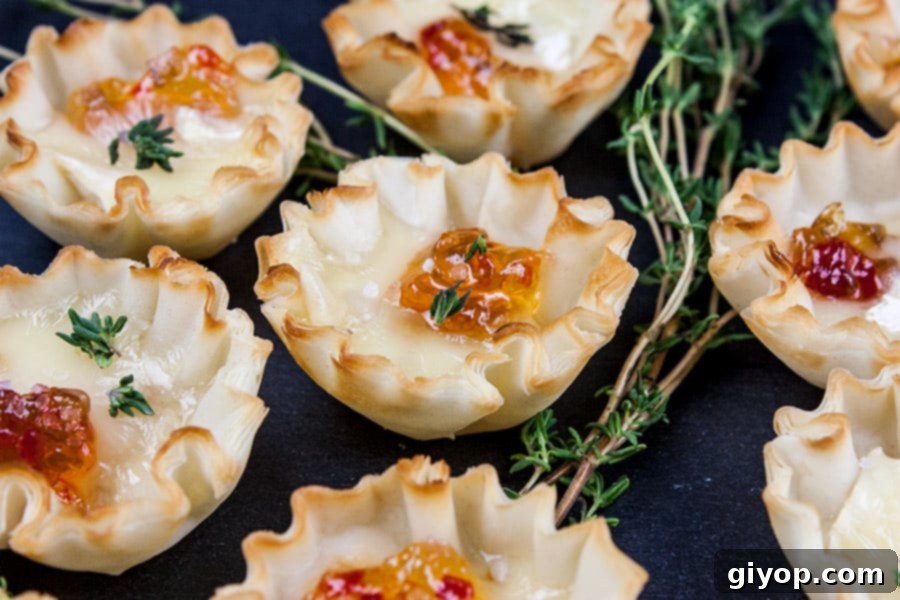 Closeup of Pepper Jelly Brie Bites on a black slate, with more focus on the top texture and garnish.