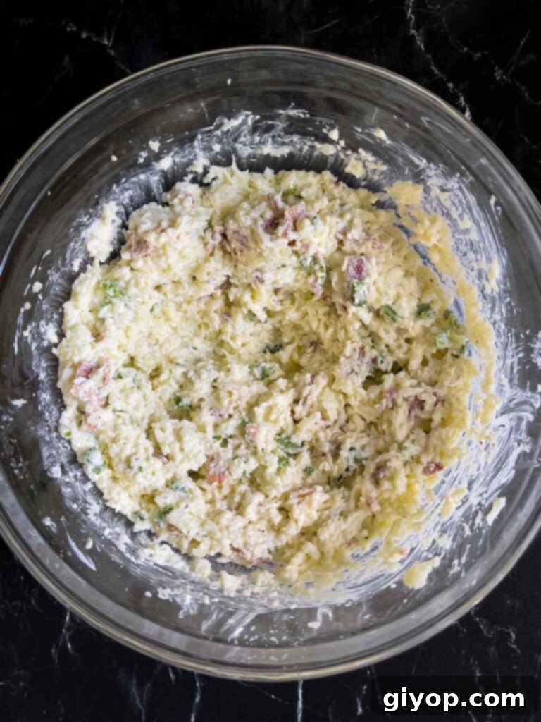 The unbaked loaded cauliflower mash casserole in a glass bowl.